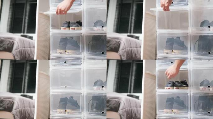特写镜头男性的手把男人的鞋子放进卧室4k的塑料盒鞋柜