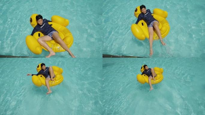 快乐的亚洲男孩在游泳池里的黄鸭橡皮筏上放松，与家人一起度假，生活方式理念。