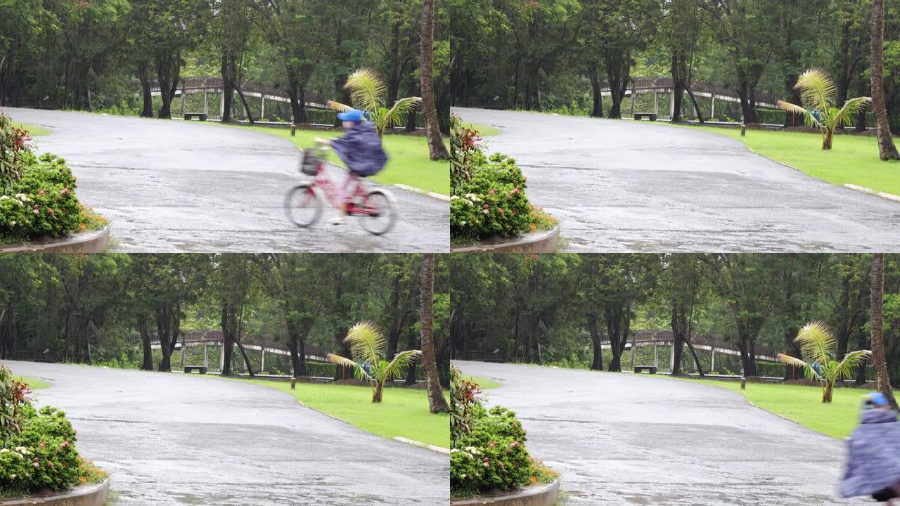 雨水滴落在地板上。夏天在公园倾盆大雨和绿树成荫。模糊的儿童在雨中骑自行车。