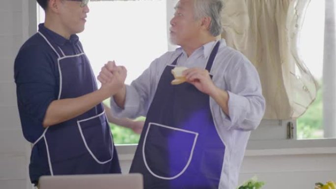 快乐的亚洲年轻人和老父亲享受周末在家厨房一起准备美味的健康沙拉