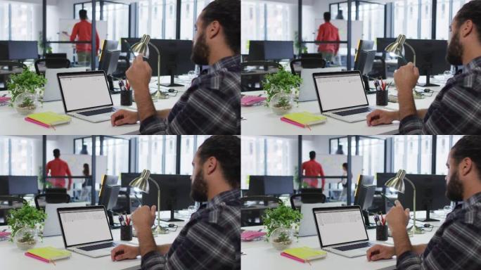 白人男子坐在办公桌前观看笔记本电脑屏幕上的编码数据处理