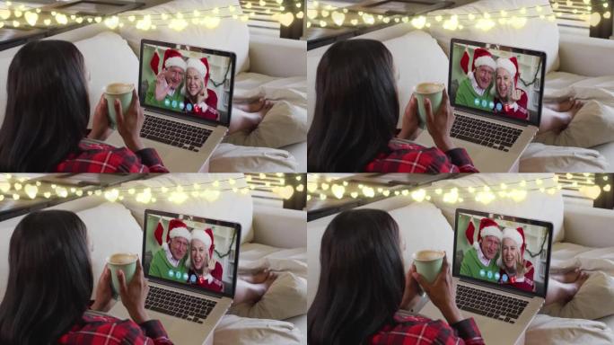 圣诞节期间，仙女照亮了拿着咖啡杯的女人，在笔记本电脑上放了一个录像带
