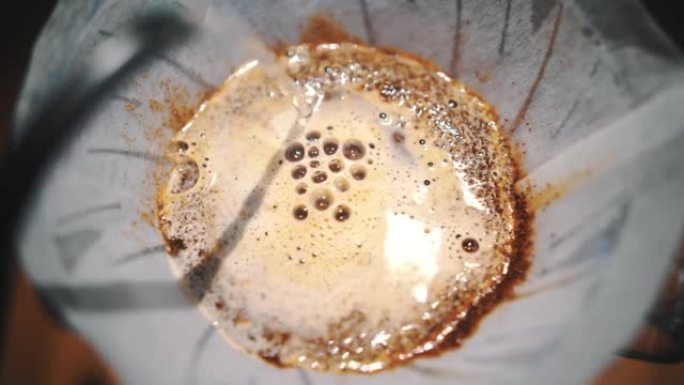 滴咖啡冲泡。特写。咖啡师在传统的滴灌冲泡设备中，将专用水壶中的沸水倒在新鲜磨碎的咖啡豆中