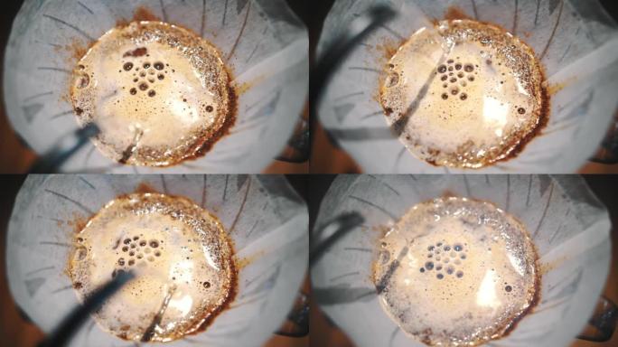 滴咖啡冲泡。特写。咖啡师在传统的滴灌冲泡设备中，将专用水壶中的沸水倒在新鲜磨碎的咖啡豆中