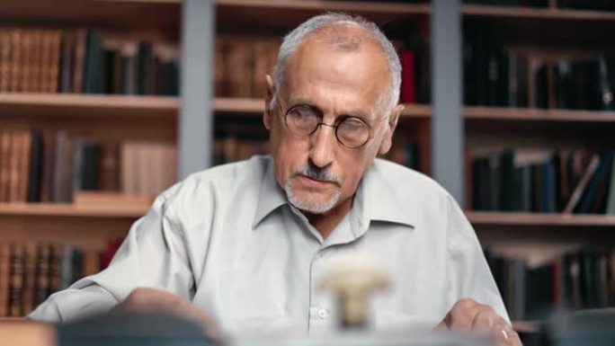 特写一位白发苍苍的老人在图书馆书桌前阅读书籍，搜寻历史研究