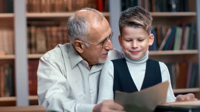 快乐的老人爷爷和小孙子在图书馆学习古玩历史文献
