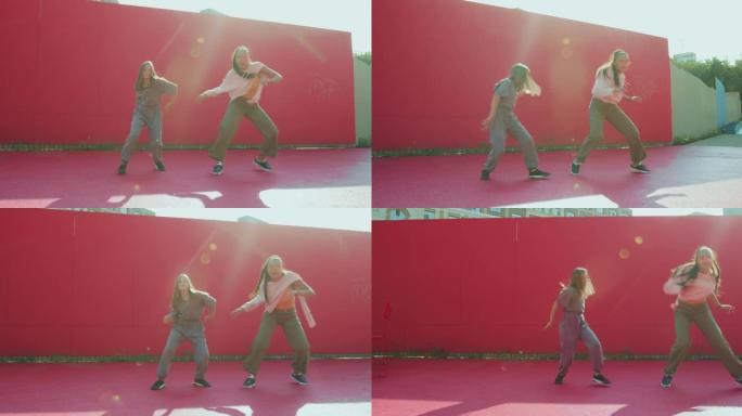 现代女舞者姐妹在阳光下在户外街头跳舞。时尚的女孩表演充满活力的舞蹈