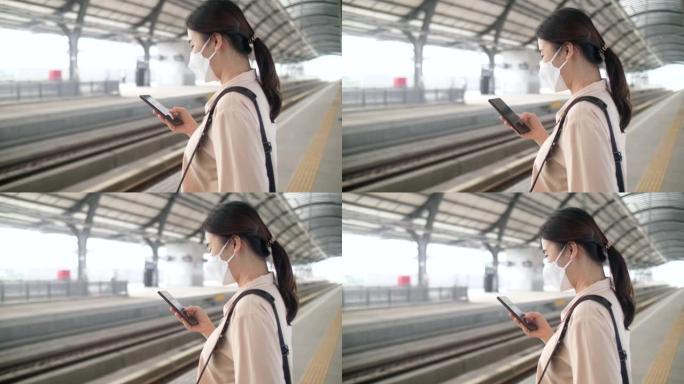 妇女在曼谷的车站使用智能手机和等候火车
