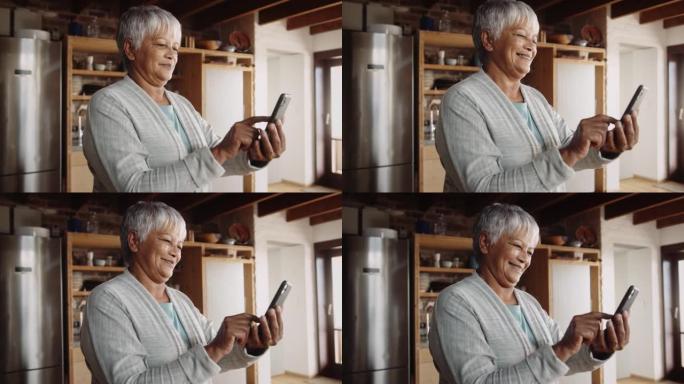 退休的多种族老年妇女在手机上留言。站在现代厨房，快乐