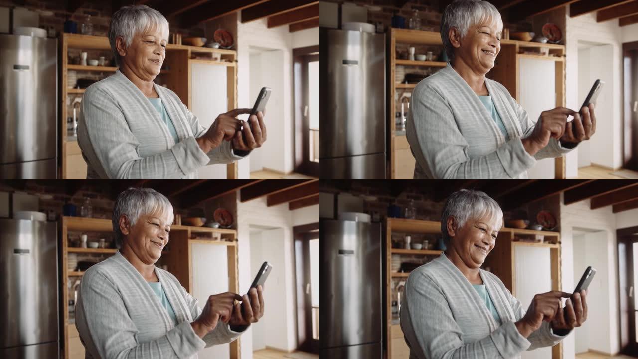 退休的多种族老年妇女在手机上留言。站在现代厨房，快乐