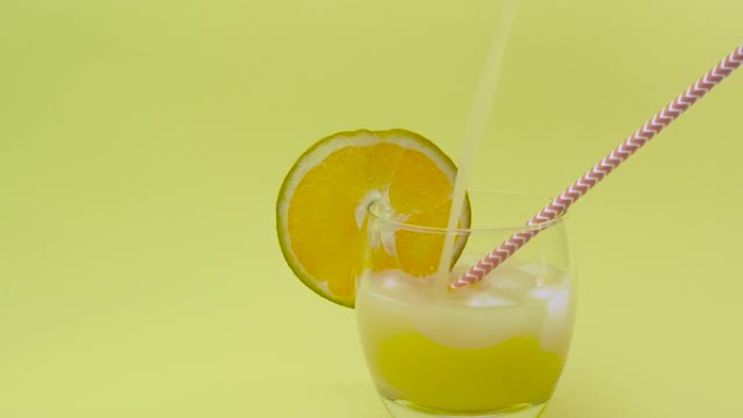 冰天然果汁。酒精饮料正在倾泻。鸡尾酒。将黄色柠檬水从水罐中倒入装有冰块的玻璃杯中。橙汁或菠萝汁