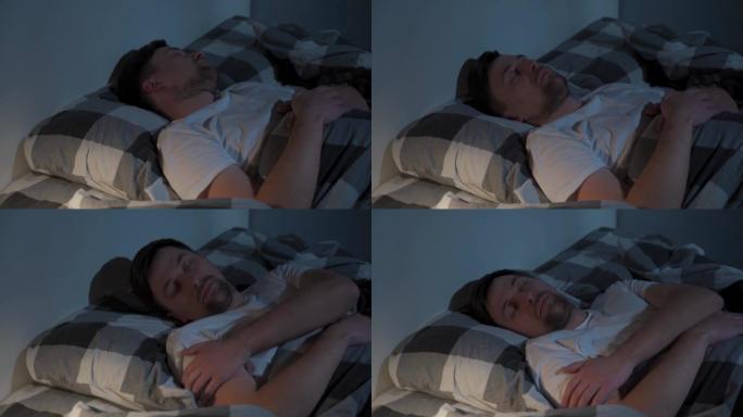 年轻的白人男子在床上旋转，不舒服的睡眠条件。紧张的人晚上睡不着，失眠。情绪和睡眠障碍概念。男性在床上