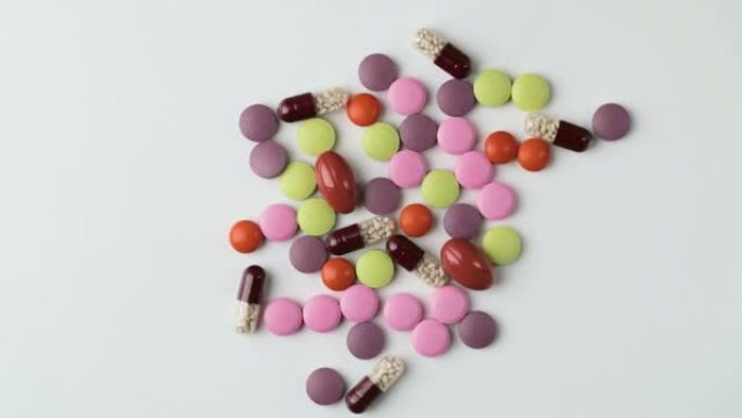 医学概念。多色药物背景。不同的彩色补救措施，药丸，抗生素和维生素在白色背景上旋转。