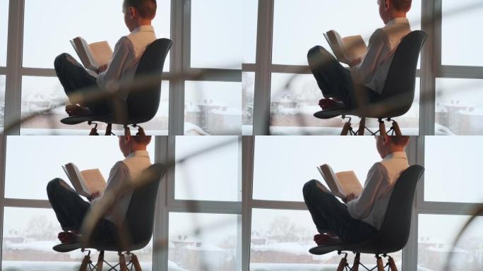 男孩读书。十几岁的男孩赤脚坐在椅子上，在明亮的房间里看书