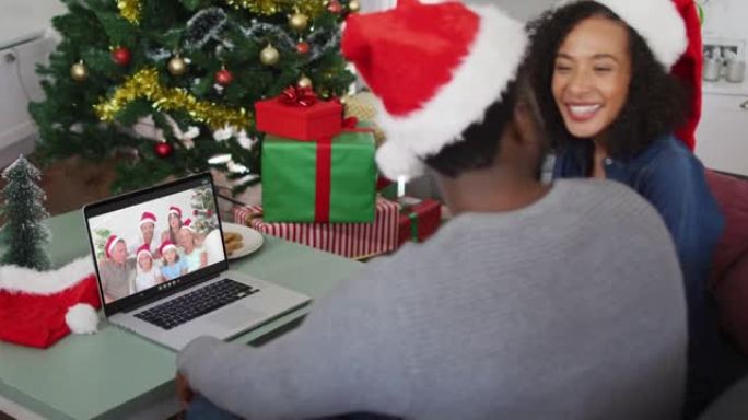 圣诞节期间，戴着圣诞老人帽子的非洲裔美国夫妇在家里的笔记本电脑上进行录像
