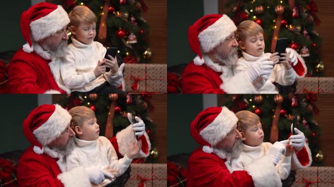 圣诞老人和一个小男孩点击智能手机，在互联网上选择圣诞礼物。电子商务。新年精神、节日和庆祝活动的概念。