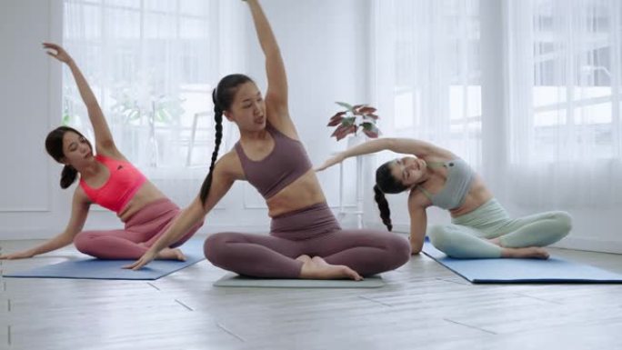 亚洲女瑜伽老师正在课堂上教学生基本练习，锻炼概念和健康