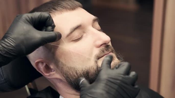 理发师在男人脸上做穿线手术