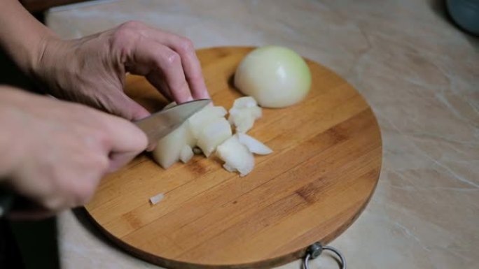 女人的手用刀在砧板上的桌子上切洋葱，洋葱头。