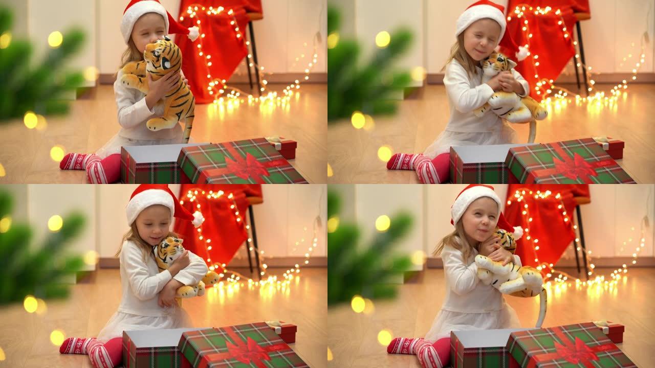 快乐的小女孩打开礼品盒，在圣诞树旁边拿出玩具老虎