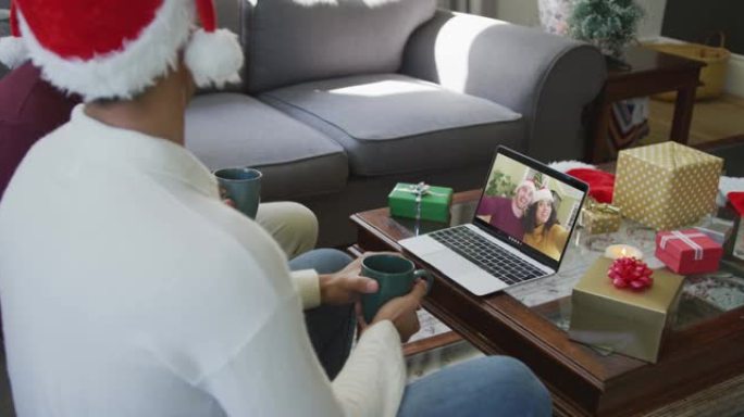 混血儿的父亲和儿子使用笔记本电脑进行圣诞节视频通话，屏幕上有微笑的夫妇