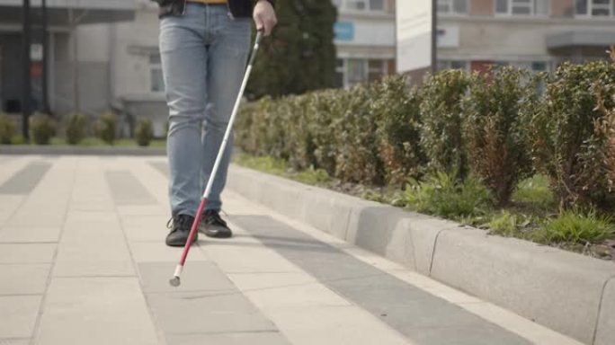 一个无法辨认的盲人独自走在城市里