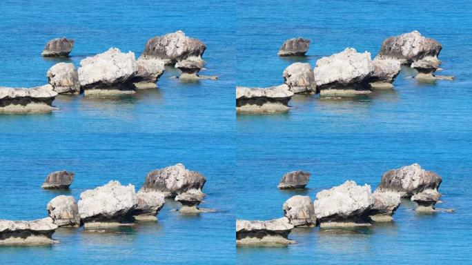 海蓝色的水和岩石的风景镜头，阳光明媚的白天海景，毁灭性的和壮观的，海浪在海岸的岩石上撞击，造成水的爆
