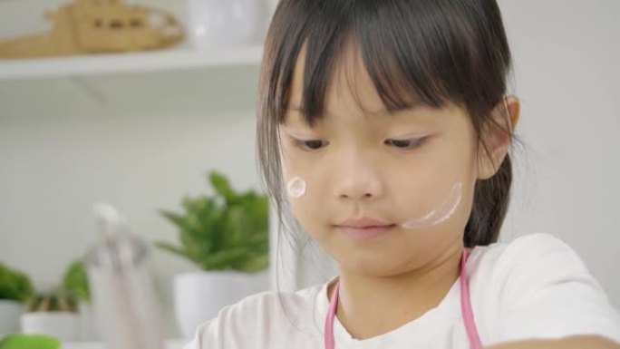 快乐的亚洲孩子在家里学习做饼干，女孩在搅拌碗里搅拌面粉。