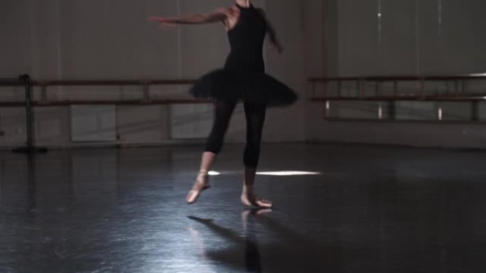 一个穿着黑色短裙的女芭蕾舞演员在工作室里跳舞