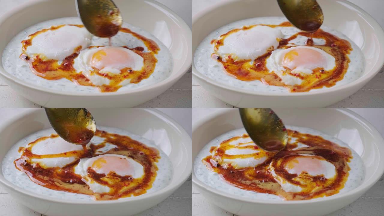在白色碗中烹饪土耳其鸡蛋cilbir。加酸奶和黄油酱的荷包蛋。