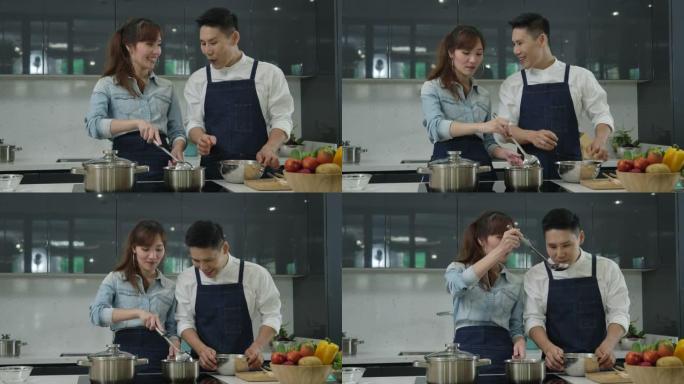 年轻的亚洲妻子和丈夫跳舞，并努力在厨房里一起做饭。