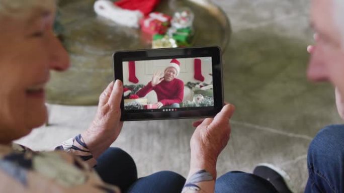 高级高加索夫妇使用平板电脑进行圣诞节视频通话，屏幕上有微笑的男人