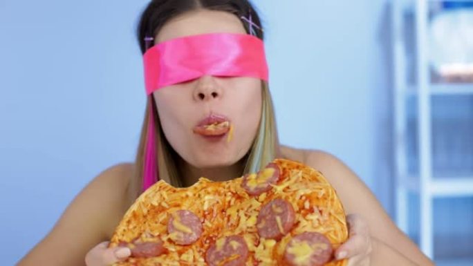 饥饿的女孩蒙着眼睛吃意大利辣香肠披萨