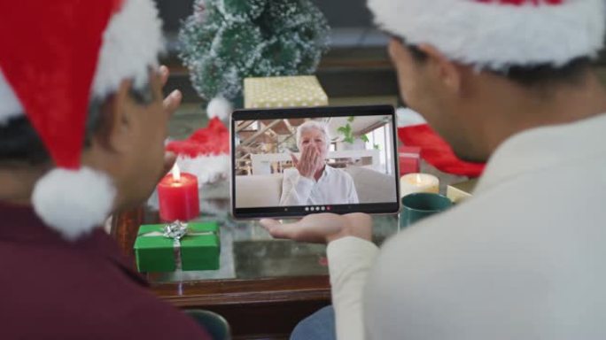 混血儿的父亲与儿子挥舞着，并使用平板电脑与屏幕上的女人进行圣诞节视频通话