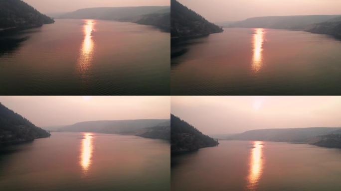 红焰色太阳在野火烟熏空中在罗斯福湖上