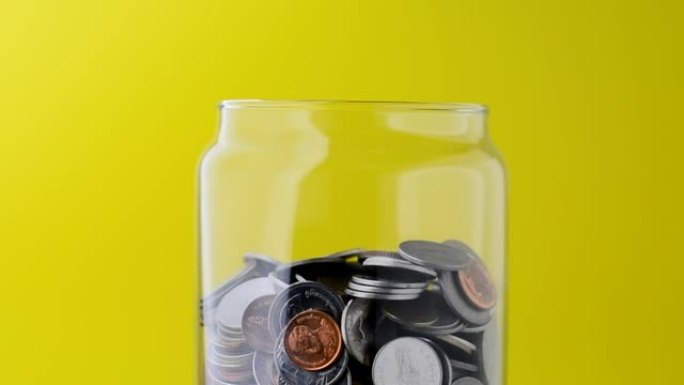 玻璃瓶中的硬币慢慢地绕着它转。玻璃瓶里的钱视频。省钱。未来的储蓄想法。