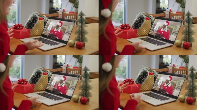 圣诞节期间，戴着圣诞老人帽子的白人妇女在家中使用笔记本电脑进行录像