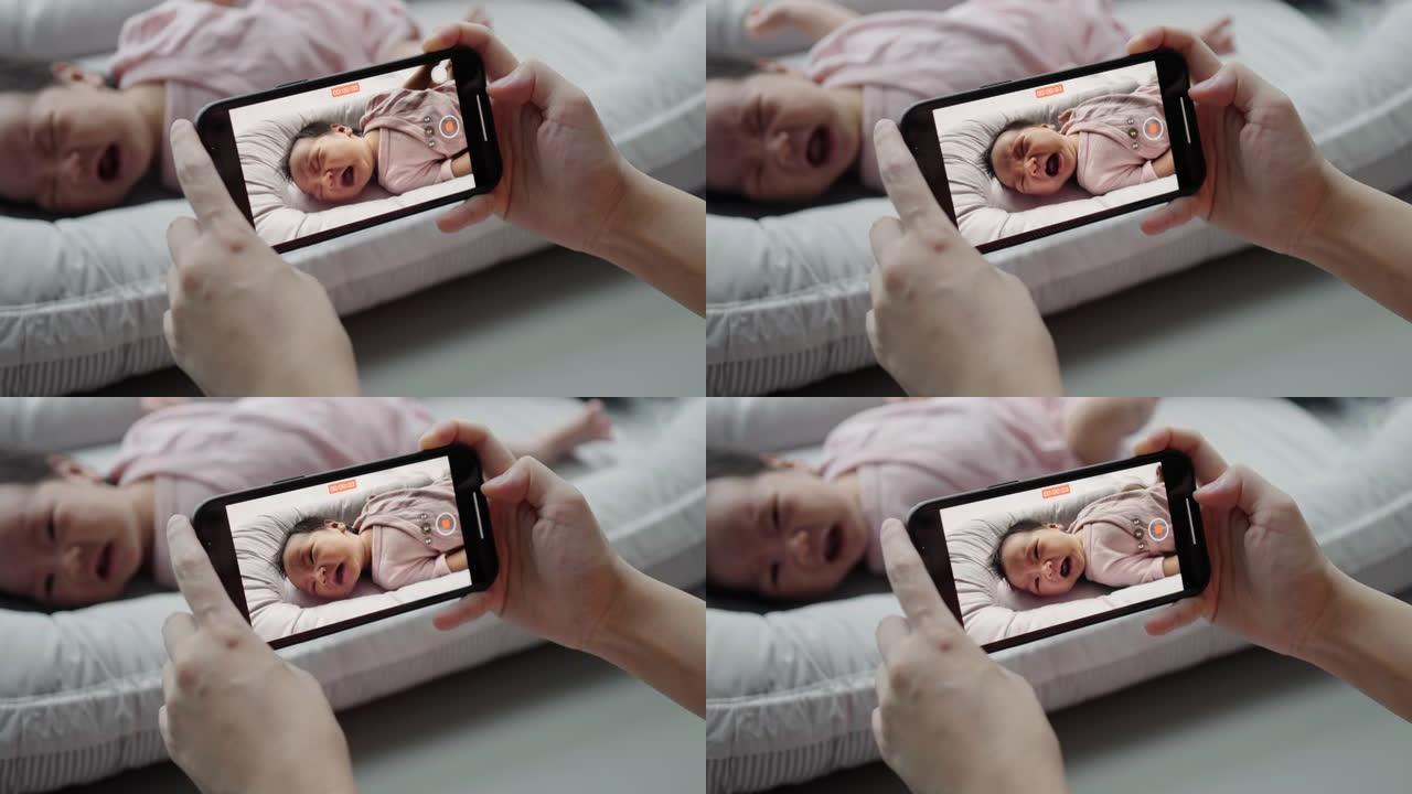 妈妈用手机按下录制躺在靠垫上的可爱的婴儿视频。