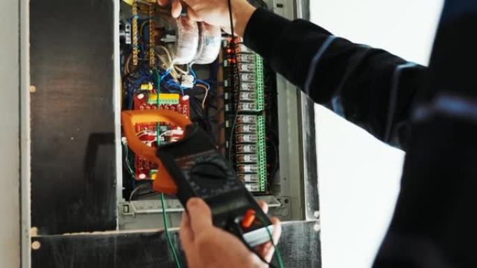 电工在控制面板中测试电流。电工工程师工作测试仪在机柜控制中测量电力线路的电压和电流。