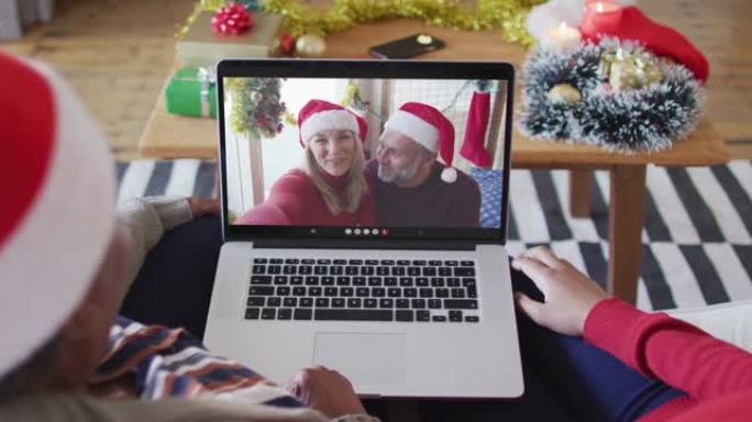 非裔美国母亲和女儿使用笔记本电脑进行圣诞节视频通话，屏幕上有情侣