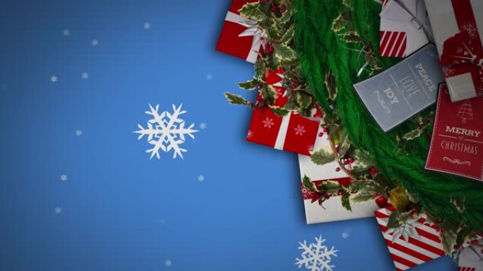 雪花落在蓝色背景下的圣诞花环装饰和礼物上