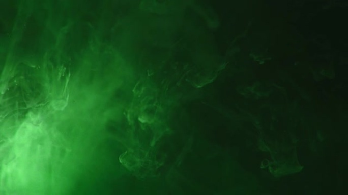 绿色油漆滴在水中慢动作混合。光滑的墨水从水下上方旋转和飞溅。黑色背景上的墨云。
