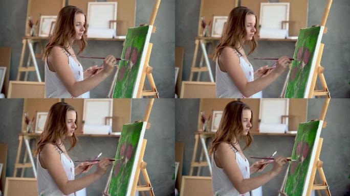 一位女艺术家的特写肖像她用画笔和画布上的丙烯酸颜料用牡丹画了一幅画。工作室里到处都是乐器。