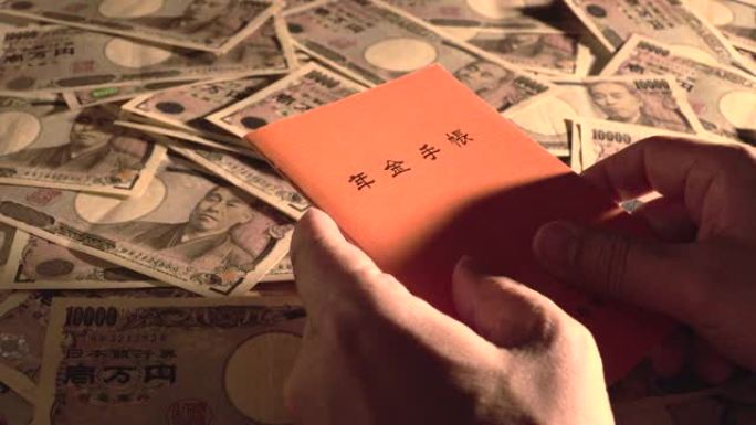 拿起养老金簿。日本国民养老金簿和10,000日元账单