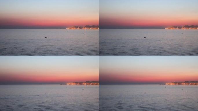 阿尔巴尼亚杜勒斯海滩的田园诗般的平静日落，背景是杜勒斯市