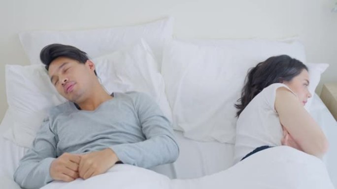亚洲年轻夫妇躺在床上，吵架后痛苦不堪。新婚男女为争吵冲突和在卧室睡觉感到心碎。家庭问题 -- 分离概