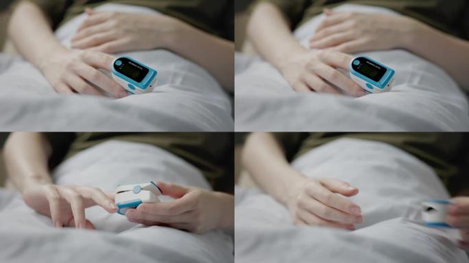 女人躺在床上，用食指的脉搏血氧仪。手的特写。实时。测定血液中氧气的概念