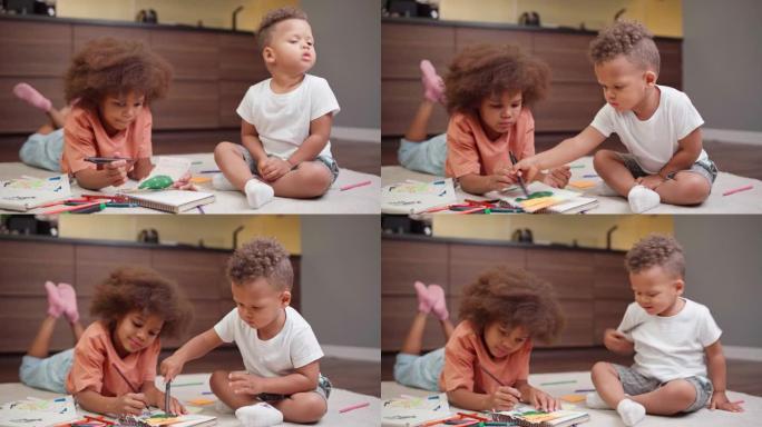 两个可爱的混血儿孩子躺在家里的地板上，用记事本的铅笔画画。富有创造力的跨种族兄弟姐妹，小女孩和蹒跚学