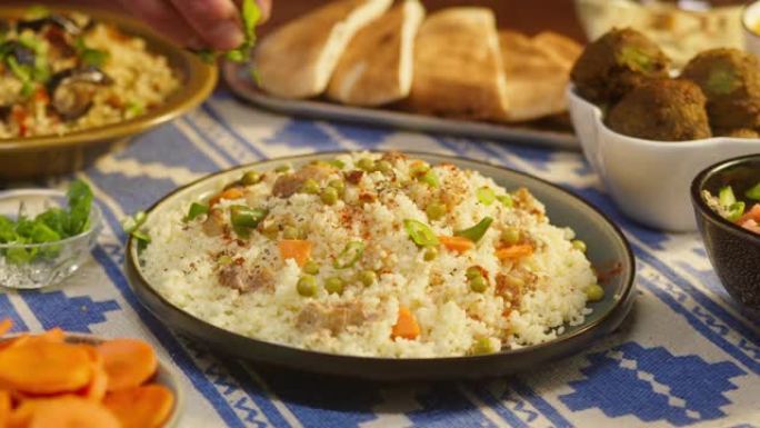 在蒸粗麦粉上撒上绿色植物，桌子上放上鸡肉。阿拉伯美食。皮塔饼和背景小麦。传统中东文化。美味的米饭和肉