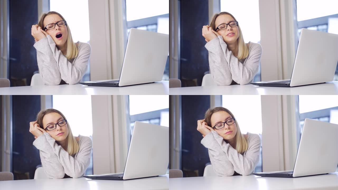 年轻的金发女人戴着眼镜在笔记本电脑上工作，伸展运动超负荷。计算机专业的女学生